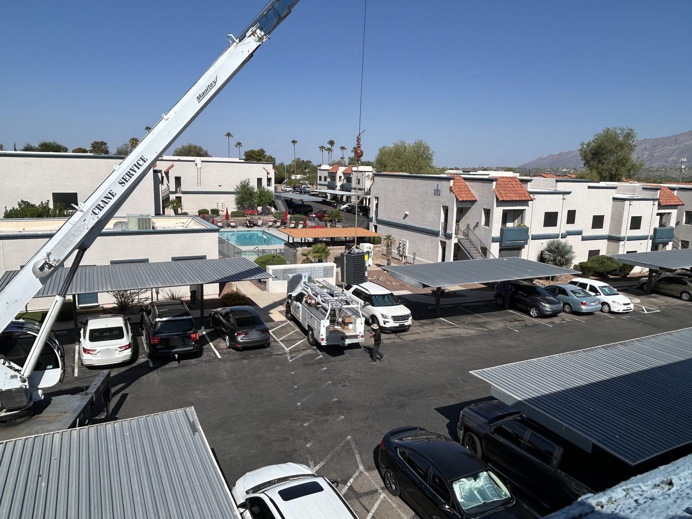 Crane lifting a new condenser onto an apartment community roof