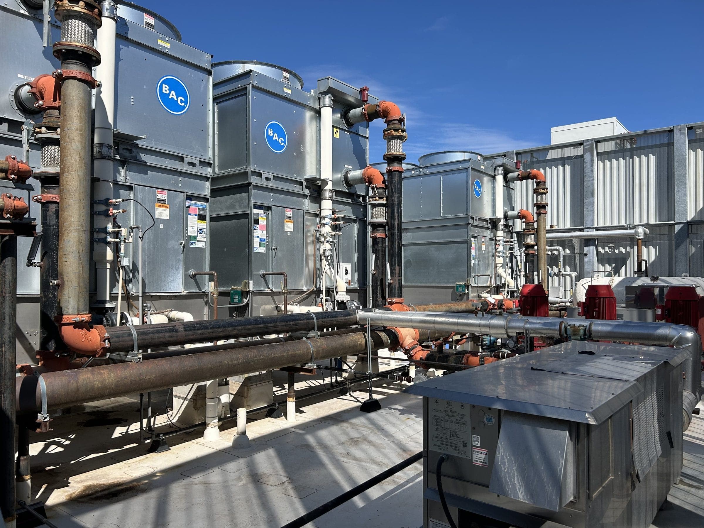 Rooftop cooling towers and water piping at a large commercial facility